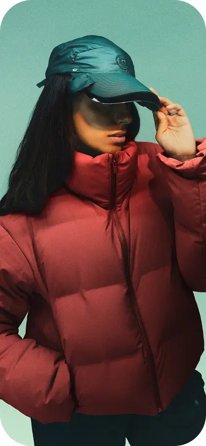 Person wearing a red puffer jacket and the Captured Cap, standing against a solid light green background.